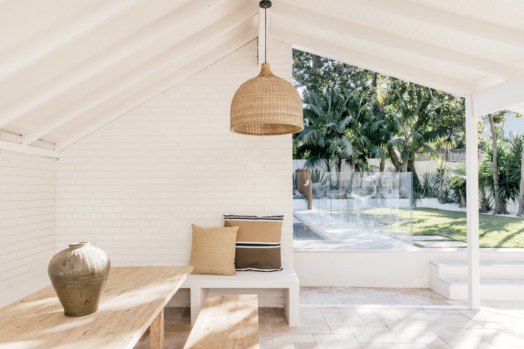 A bright, tidy covered outdoor room opening onto a lawn and pool